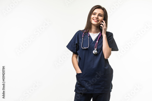 Young doctor woman keeping a conversation with the mobile phone on grey background