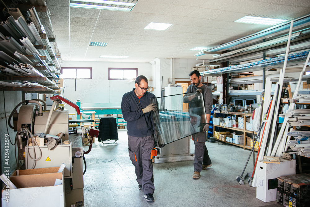 Male workers with aluminum window glass in workshop Male workers with aluminum window glass in workshop