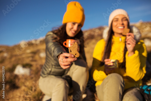 Two happy female hikers eating cookies outdoor