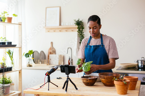 Black woman showing green plant to vlog audience photo