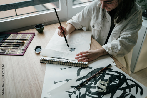 Young woman writing japanese kanji characters with a brush and ink photo