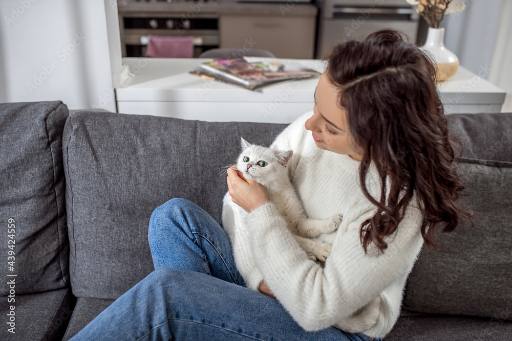 Cute young woman spending weekend at home with her cat