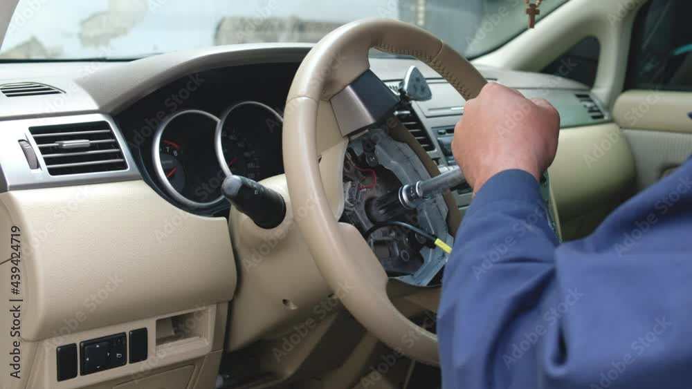 Auto mechanic spins the steering wheel of a car with a ratchet key