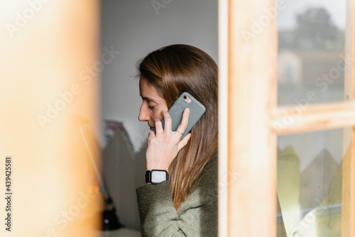 Young woman speaking on smartphone on bed
