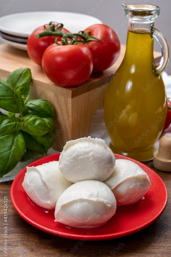 Cheese collection, small fresh white soft mozzarella cheese balls served with red tomatoes and fresh green basil from Italy