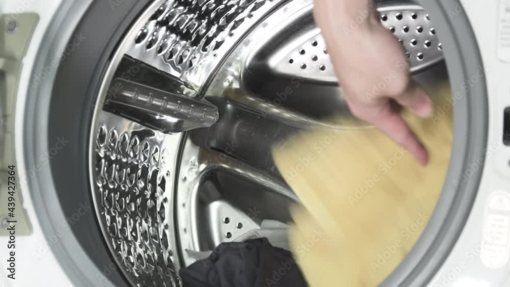 Putting the dirty clothes in the washing machine. Front load washer machine.