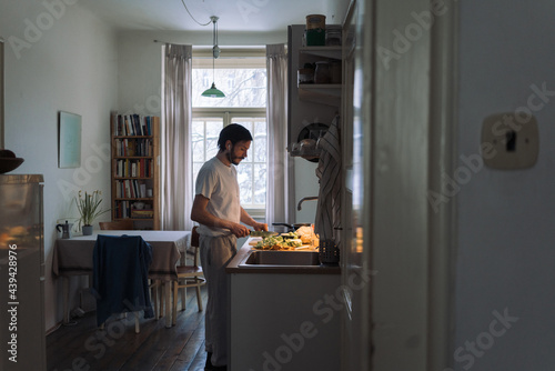 Man in his 30's preparing a lunch at his home, listening to music on headphones photo