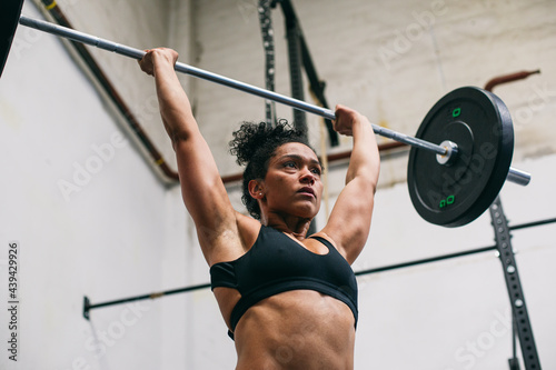 Hispanic female athlete exercising with barbell