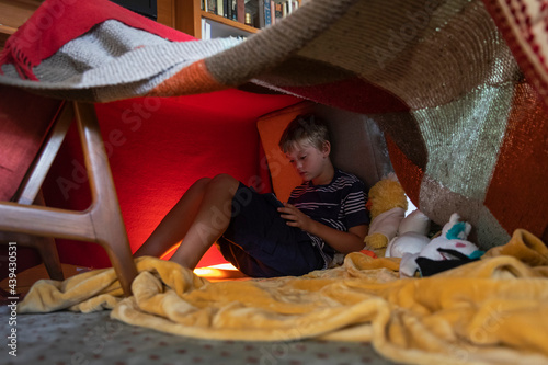 Wide angle of Child Watching Ipad Tablet inside Homemade Tent Fort at Home 