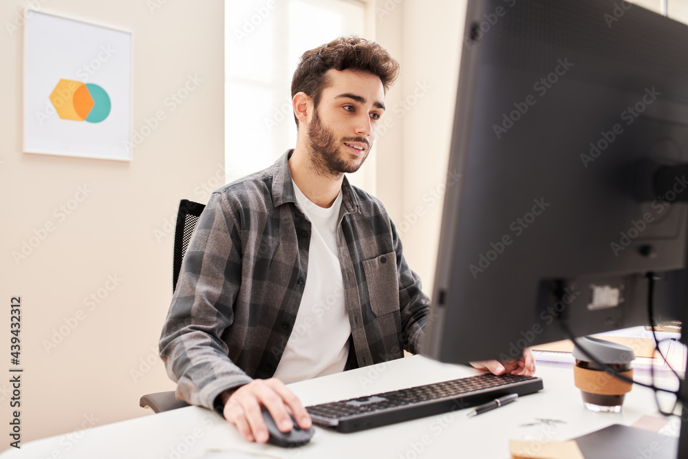 Glad young man browsing computer in home office Glad young man browsing computer in home office