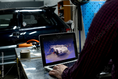Crop view of man working with 3D model of car made by pointcloud inside of service station  photo