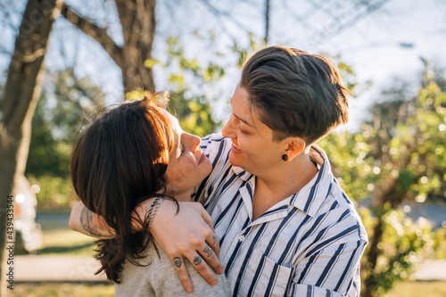 Happy lesbian couple hugging outside in sunlight photo