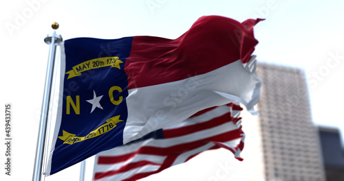 The flags of the North Carolina state and United States of America waving in the wind. Democracy and independence.