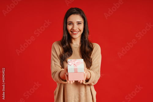 Attractive young woman in casual clothing holding gift box and smiling © gstockstudio
