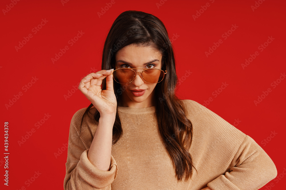 Beautiful young woman in casual clothing looking at camera and adjusting eyewear Beautiful young woman in casual clothing looking at camera and adjusting eyewear