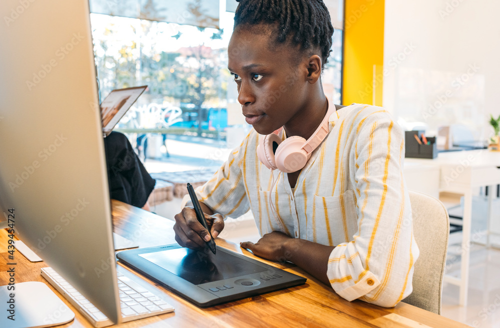 © VICTOR TORRES/Stocksy - Focused black woman working with stylus on graphic tablet