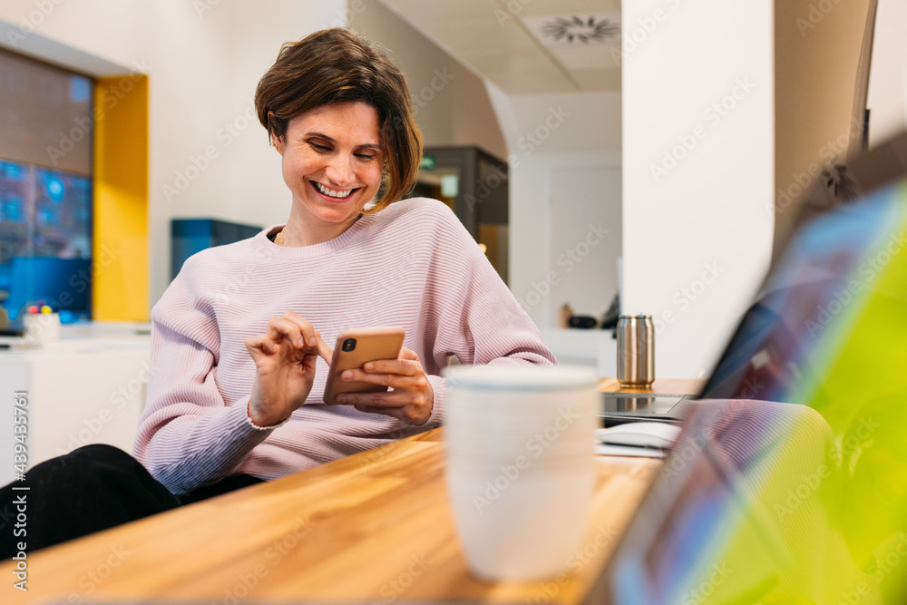 Smiling woman working on computer and browsing cellphone Smiling woman working on computer and browsing cellphone