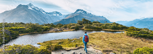 New Zealand Hiking. Young hiking man walking on trail at Routeburn Track during sunny day. Hiker tramping Key Summit Track in Fiordland National Park in New Zealand. Panoramic banner