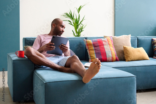 Black man with ipad on couch at home