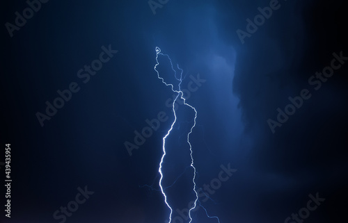 Lightning in the night sky. Thunderstorm over the city. Stormy clouds and rainy weather.