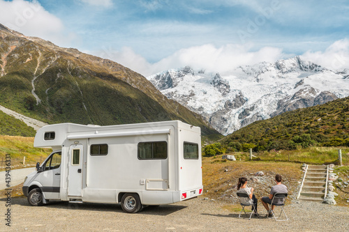 Motorhome camper van RV road trip on New Zealand. Couple on travel vacation adventure. Tourists looking at view of Aoraki Mount Cook National park and mountains on pit stop next to their rental car