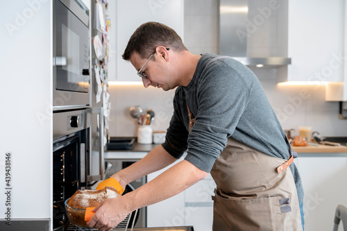 Man taking bread out of oven photo