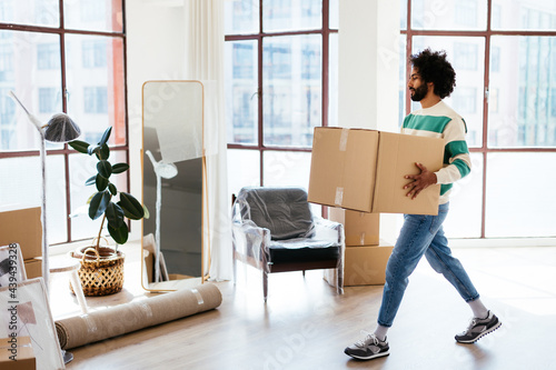 Black male carrying box in new apartment photo