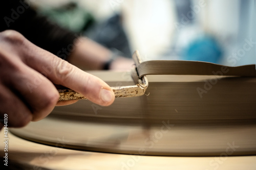 Person filing a ceramic piece ina workshop photo