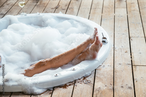 Crop woman relaxing in hot tub with foam