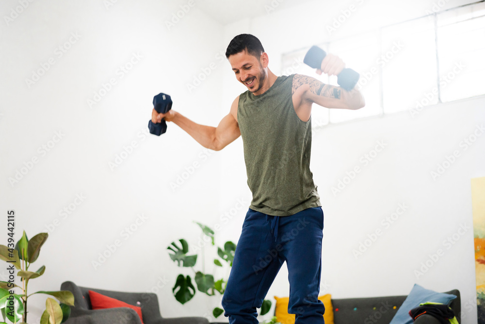 Tattooed man exercising with dumbbells at home Tattooed man exercising with dumbbells at home
