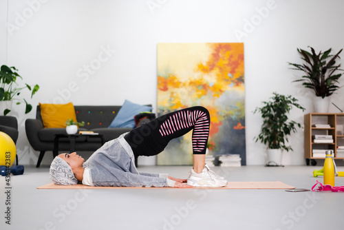 Islamic sportswoman doing hip bridge at home