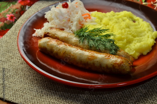 Grilled sausages and mashed potato with addition spices and fresh herbs, on rustic background photo