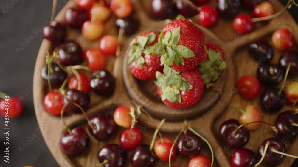 menazhnitsa with red strawberries and cherries on a dark background. Wooden plate made with compartments for snacks. menazhnitsa with red strawberries and cherries on a dark background. Wooden plate made with compartments for snacks.