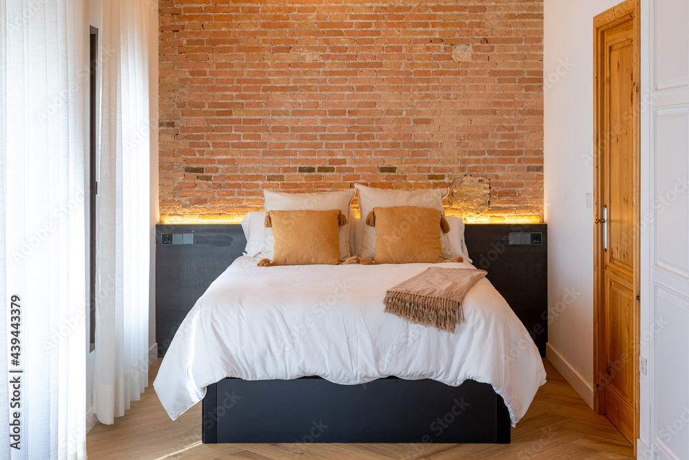 © Bisual Studio/Stocksy - Bed near brick wall in bedroom