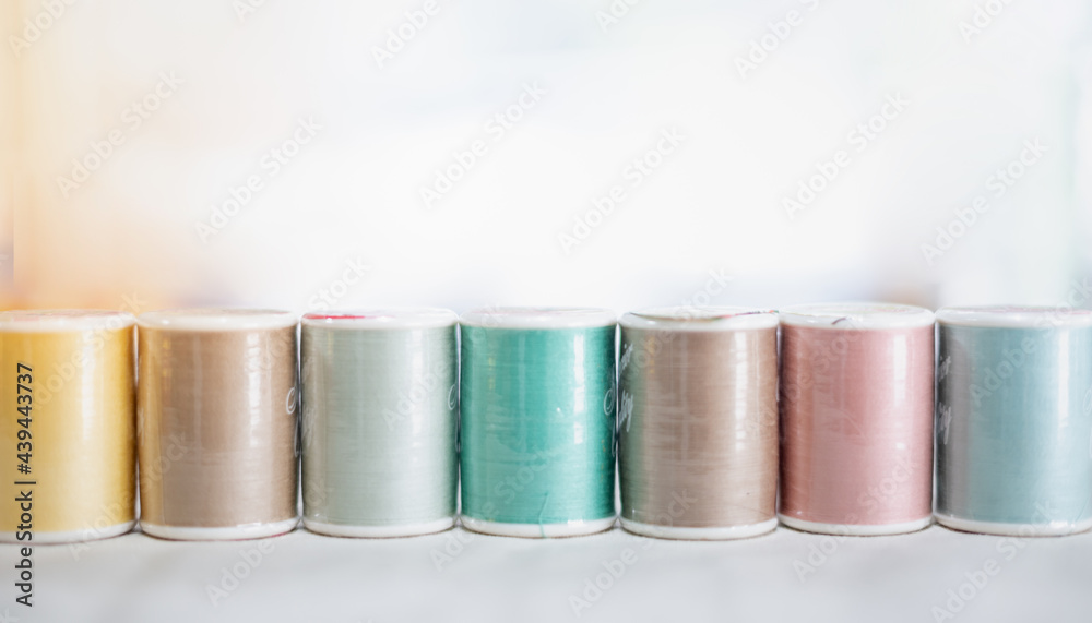 The pastel color embroidery thread spool using in garment industry, row of multicolored yarn rolls, sewing material selling in the market The pastel color embroidery thread spool using in garment industry, row of multicolored yarn rolls, sewing material selling in the market