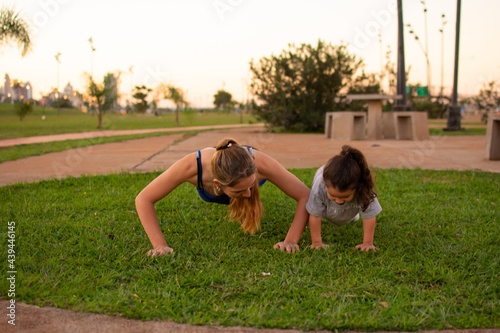 madre e hija haciendo flexiones de brazos en un parque al aire libre  photo
