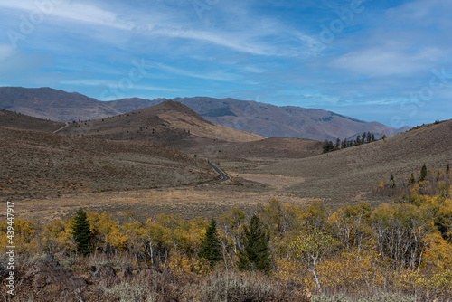 Overview from Monitor Pass in California, USA, showig rocky terrain of the Sierra Nevada and partly cloudy sky in the Autumn, featuring yellow aspen foliage and lots of sky copy-space 