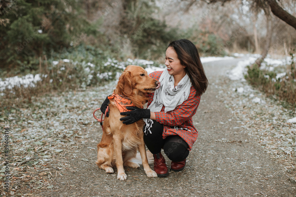 Smiling Woman Sitting with Dog on Winter Path Smiling Woman Sitting with Dog on Winter Path