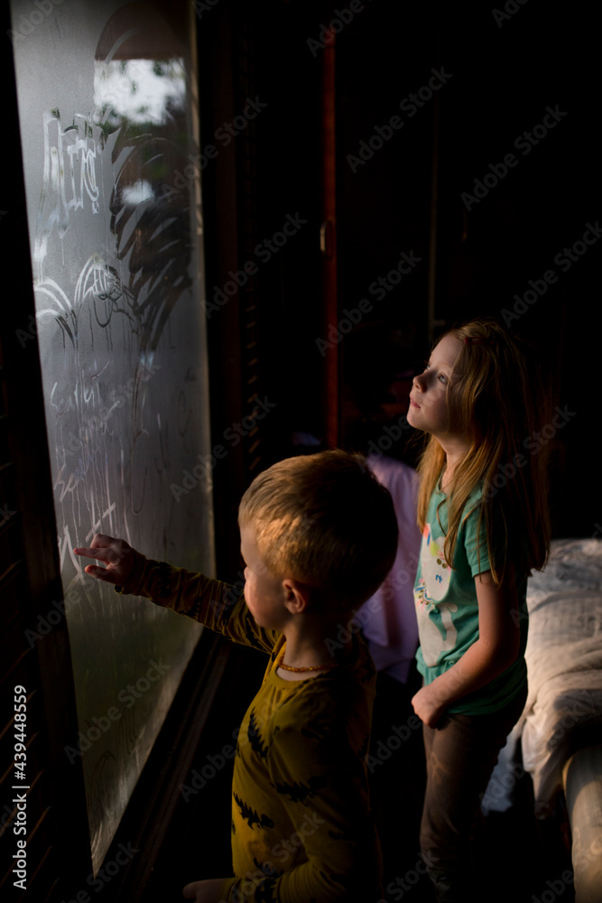Two Children drawing on steamy windows Two Children drawing on steamy windows