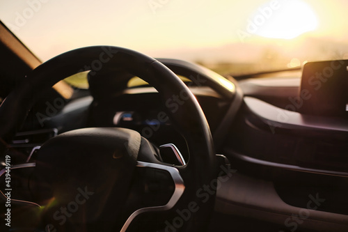 photograph of steering wheel and console of a car riding on the freeway in sunrise .shot with vary shallow focusing that keep most of photograph out of focus blurred © photopk