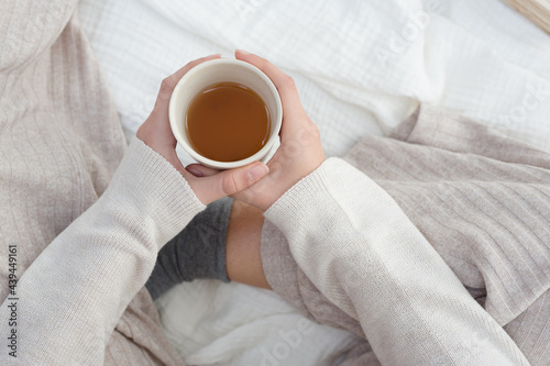 A woman's hand holding warm cup of tea