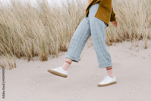 Trendy Young woman's leg wearing blue pants and white sneakers  photo