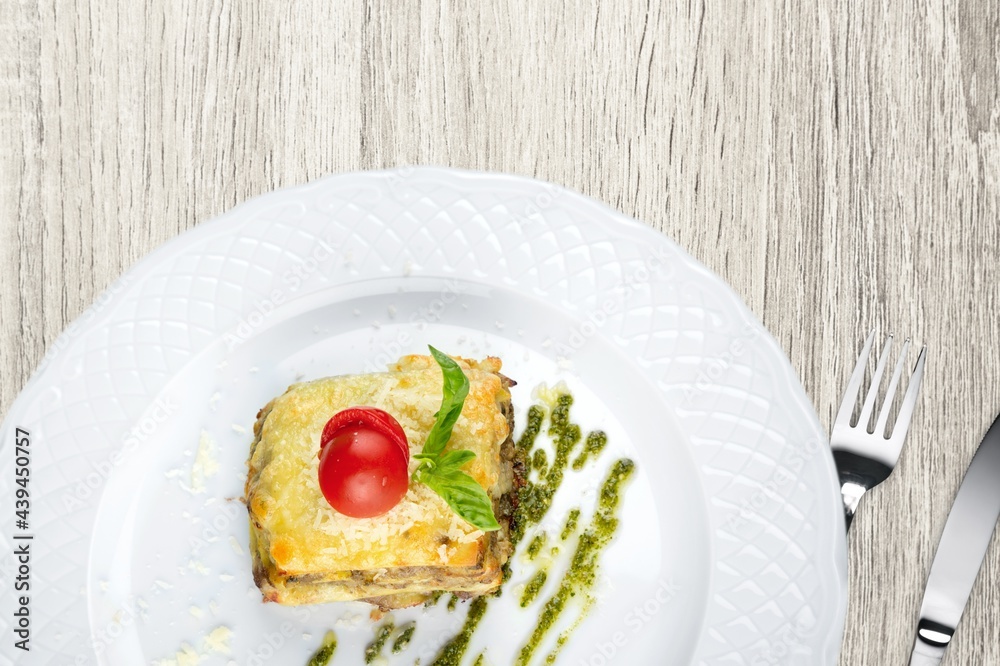 Tasty hot lasagna dish with tomato sauce and cheese served with tomatoes on a plate Tasty hot lasagna dish with tomato sauce and cheese served with tomatoes on a plate