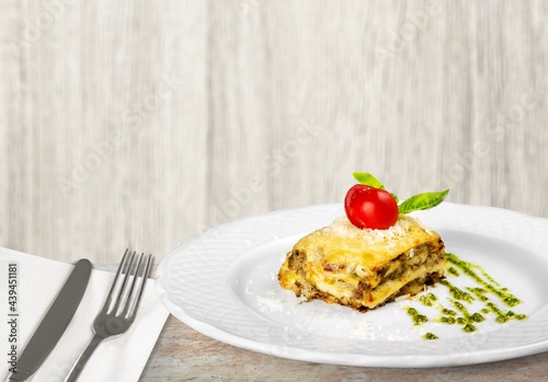 Tasty hot lasagna dish with tomato sauce and cheese served with tomatoes on a plate