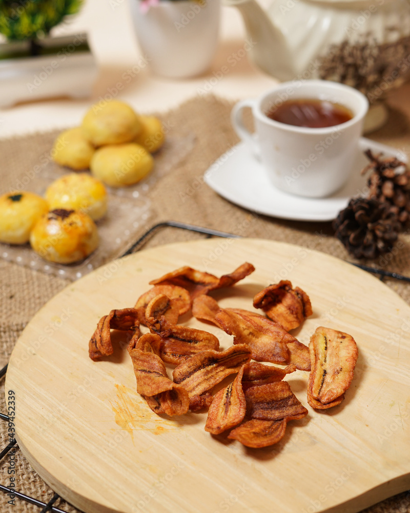 Fototapeta premium Banana chips with a bright theme. Thin slices of banana fried until brown make it crunchy. Healthy dry snacks that don't make you sleepy. Perfect as a snack when gathering with friends or family.