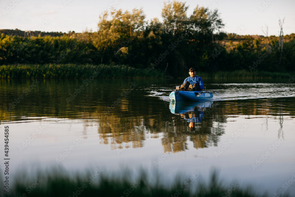 Male angler resting on boat in evening Male angler resting on boat in evening
