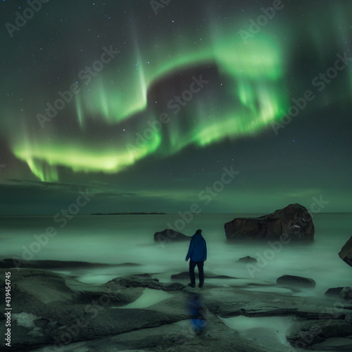 Man watching northern lights at uttakleiv beach in Norway photo