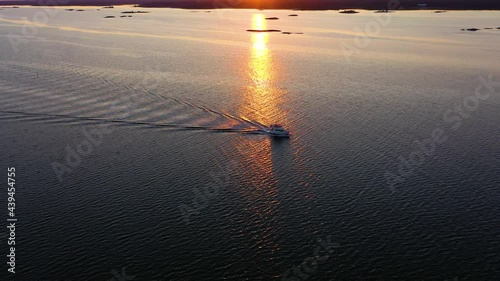 Aerial view of a boat driving in calm, reflecting sea, sunset in Scandinavia - tracking, drone shot photo