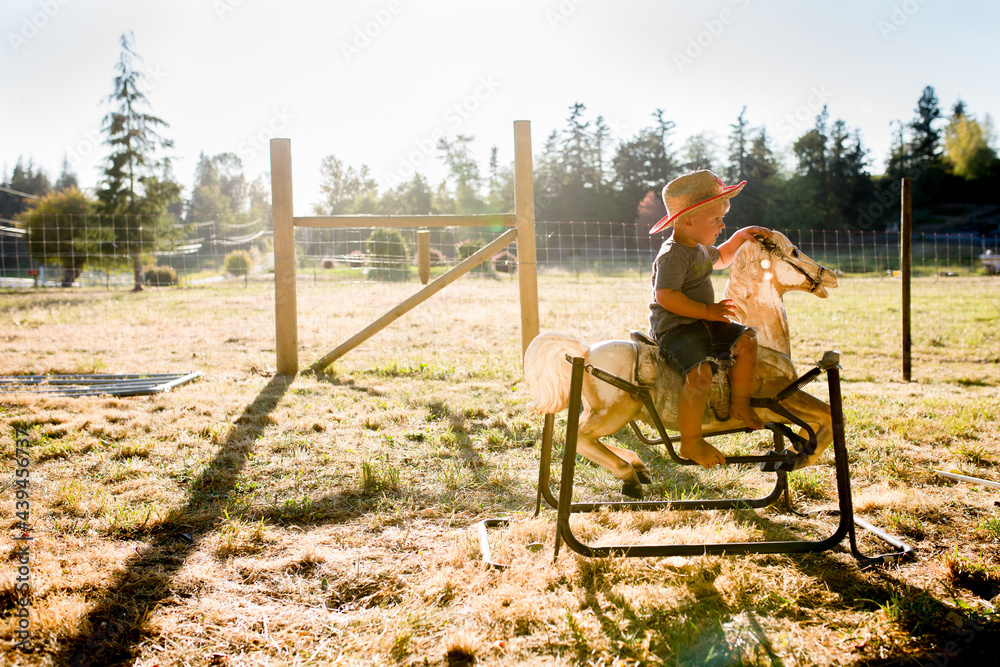Cute boy in cowboy hat rides on rocking horse Cute boy in cowboy hat rides on rocking horse