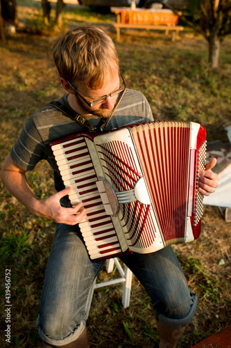 Bearded man plays accordion outdoors